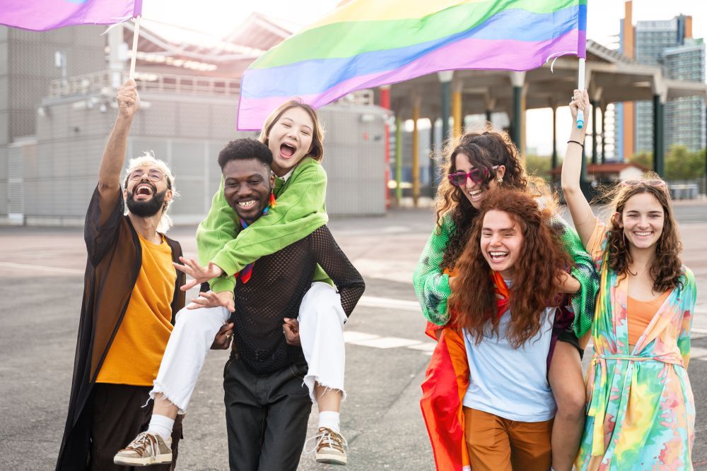 Eine Gruppe von Menschen mit Regenbogenflaggen, die miteinander lacht. 
